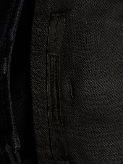 Close-up detail of a black textured fabric garment, showing a vertical stitched strap or zipper pull on a dark woven textile.
