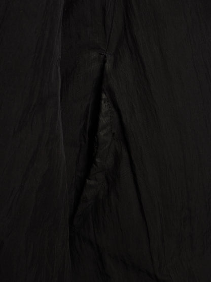 A close-up of a black crinkled fabric, showing the texture and folds of a garment or textile.
