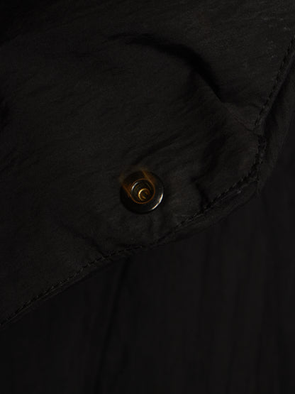 Close-up of a black garment with a small metallic snap button detail.
