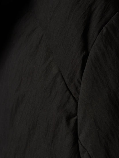 Close-up of a black crinkled fabric texture with soft folds and shadows.