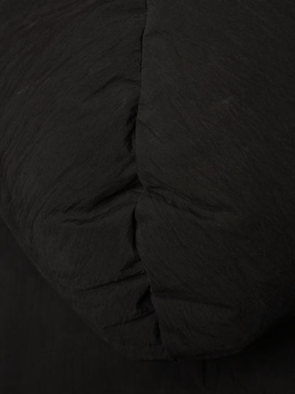 Close-up of a black quilted fabric surface with visible stitched padding and a crinkled texture.