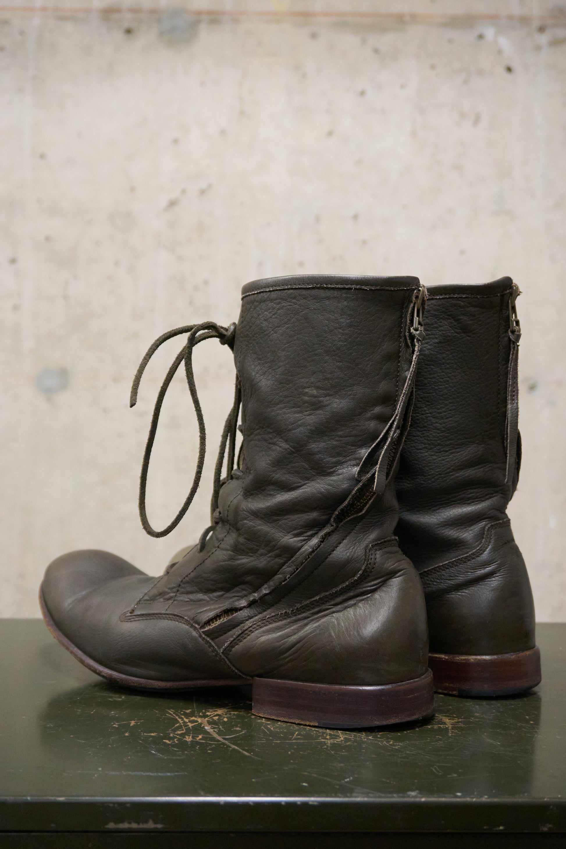 Pair of black leather boots on a textured surface with a neutral background