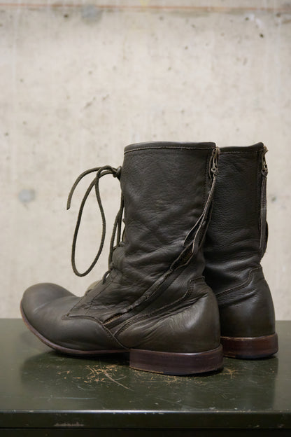 Pair of black leather boots on a textured surface with a neutral background
