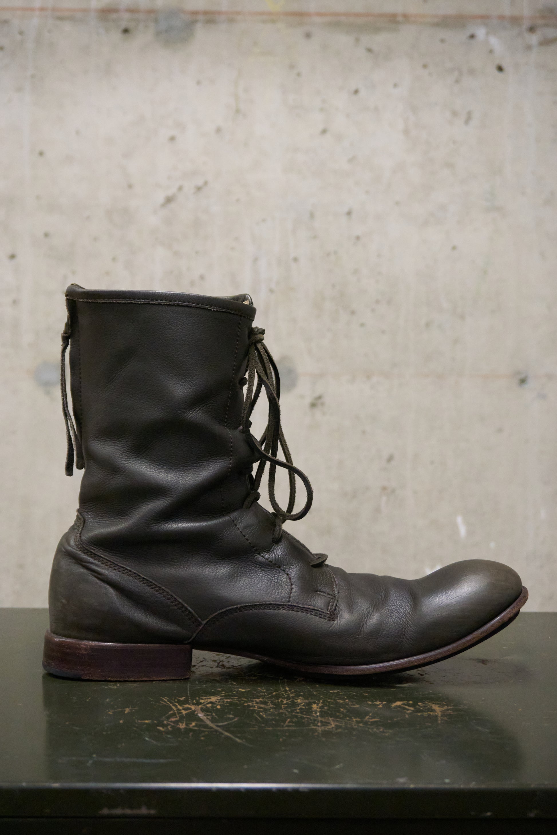 Black leather boot with laces on a textured surface