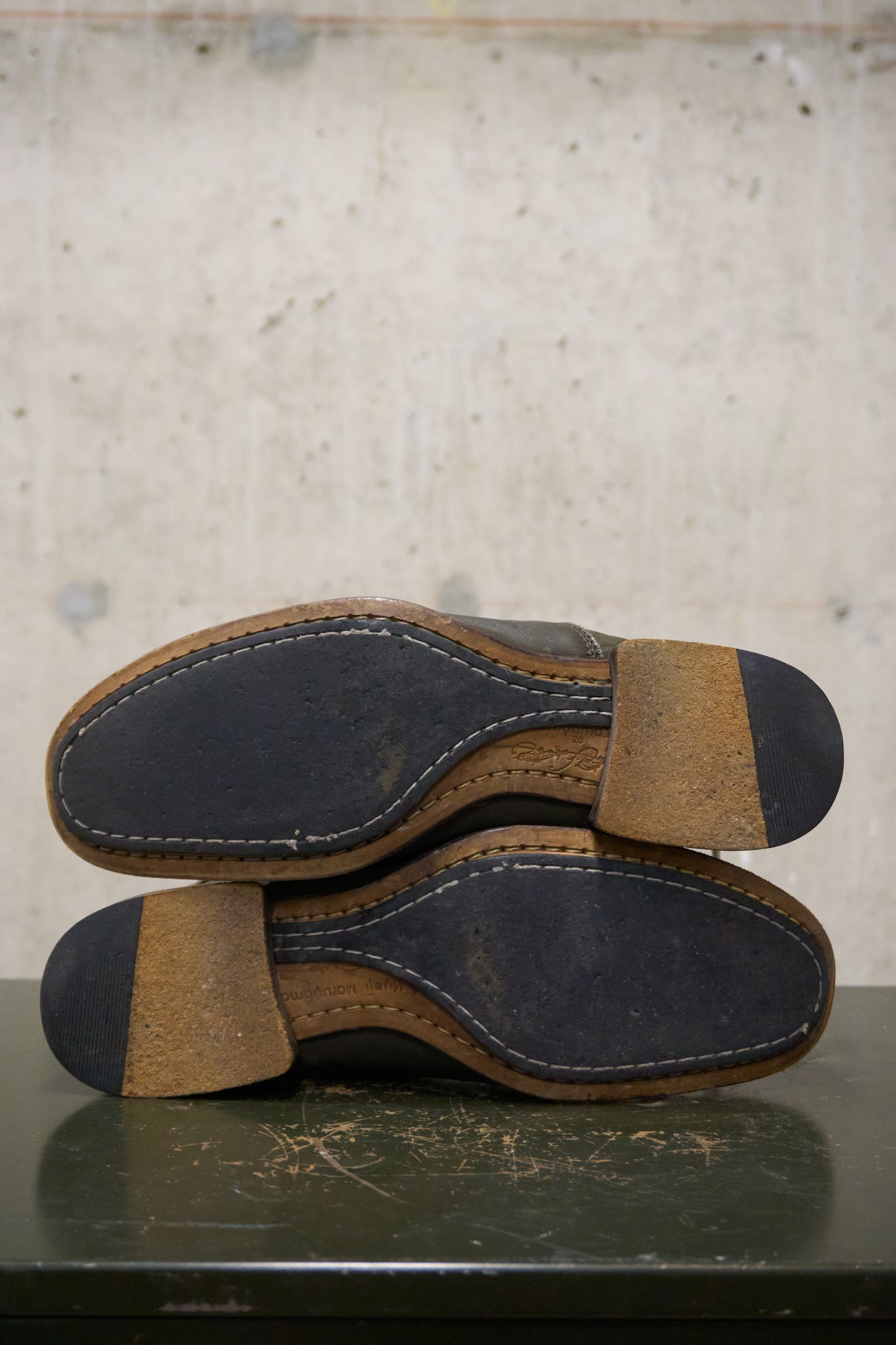 Pair of brown leather shoes with black soles on a textured surface.
