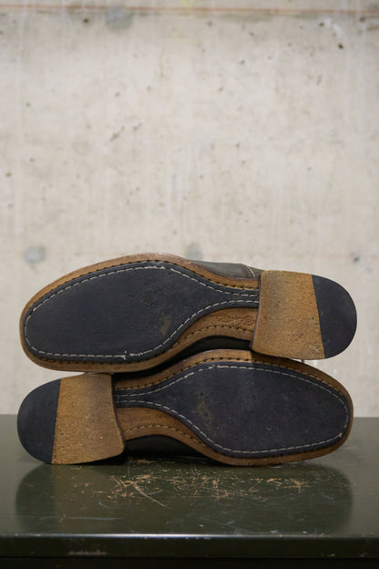 Pair of brown leather shoes with black soles on a textured surface.