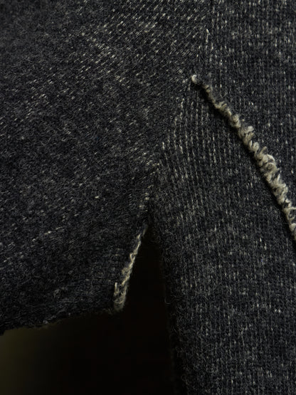 Close-up of a dark charcoal gray knit fabric with a visible frayed edge and textured weave.