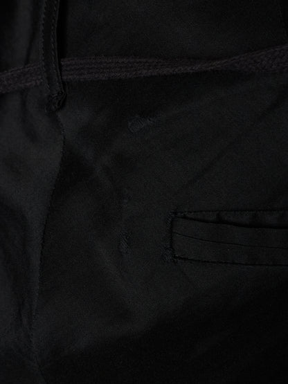 Close-up detail of a black fabric garment showing a stitched pocket and dark drawstring.