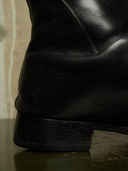 Close-up detail shot of a black leather boot showing the heel, sole, and textured leather grain.