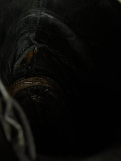 Close-up view inside a dark boot or shoe showing the interior lining, stitching, and a small worn brown area near the opening.