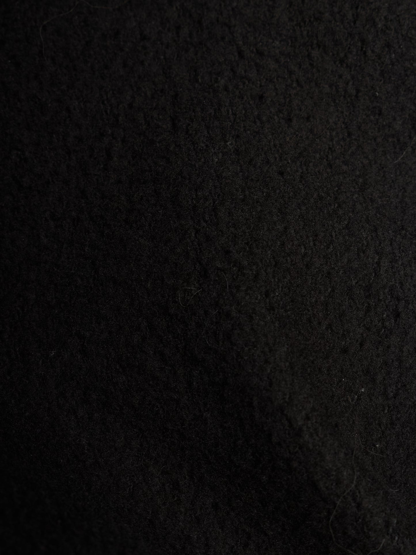 A close-up texture shot of a black felt or wool-like fabric surface.