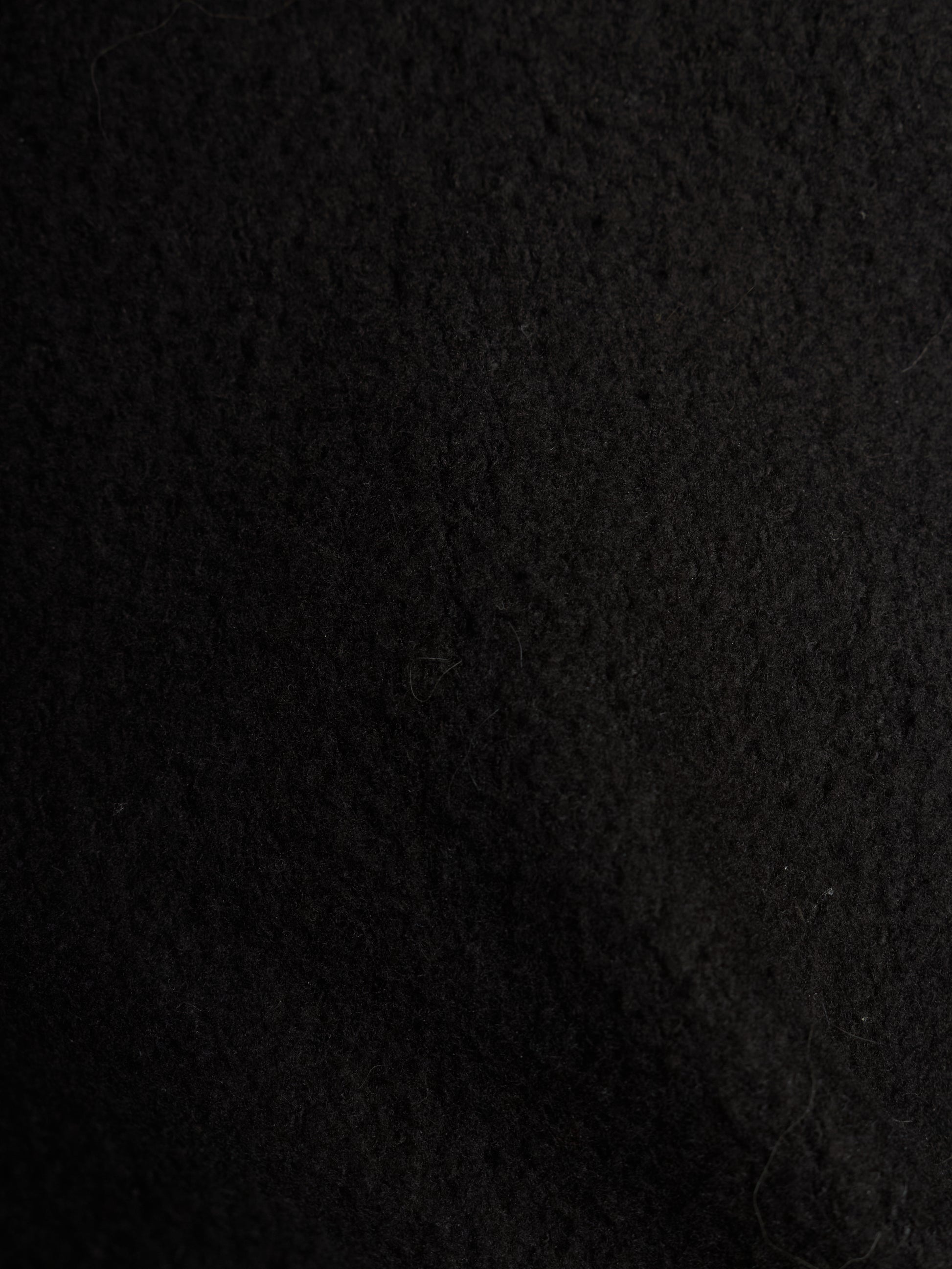 A close-up texture shot of a black felt or wool-like fabric surface.
