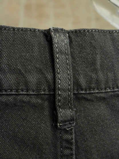 Close-up detail of a pair of dark gray or black denim shorts showing the waistband, belt loop, and stitching.