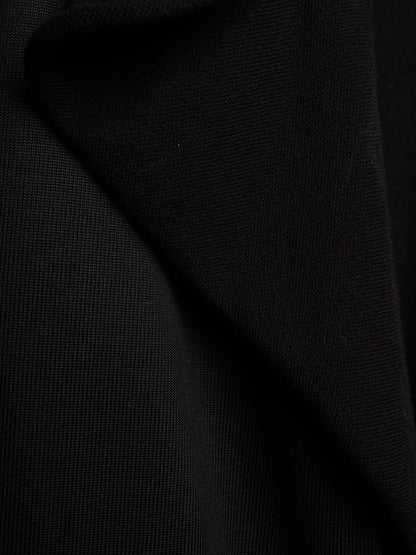 A close-up of black textured fabric with soft folds and a fine woven surface.
