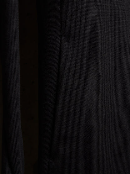 Close-up of a dark ribbed knit fabric with a fine vertical texture and a subtle seam running down the center.