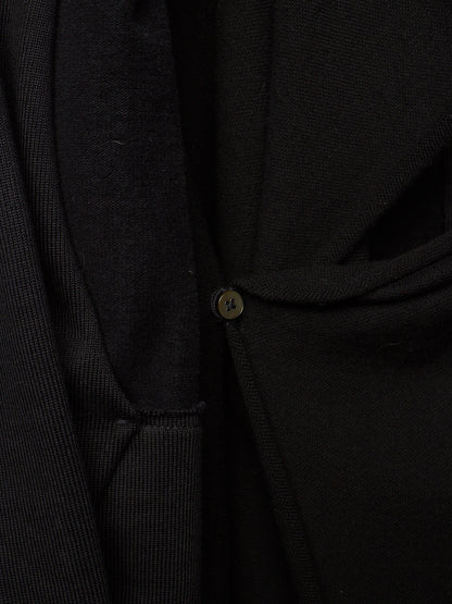 Close-up detail of a black knit garment with a small round button closure.