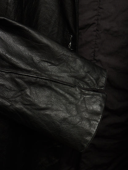 Close-up detail of a black leather jacket sleeve with a flap pocket and a black quilted puffer jacket layer underneath.