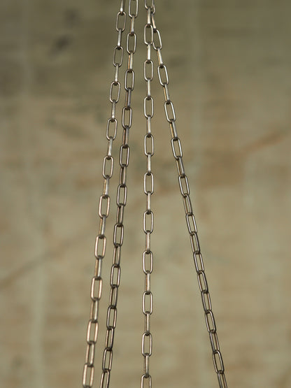 Three hanging metal chains with elongated oval links, shown against a softly blurred beige background.