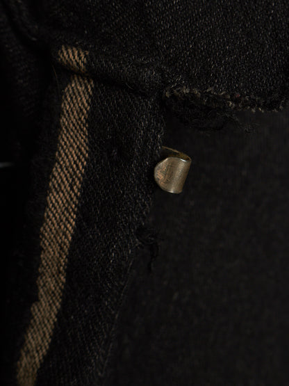 Close-up of a black woven textile with a vertical tan stripe and a small metallic loop detail.