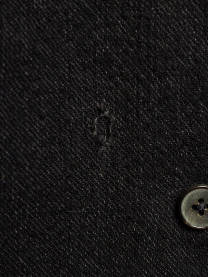 Close-up of a black textured fabric surface with a small button visible at the lower right.