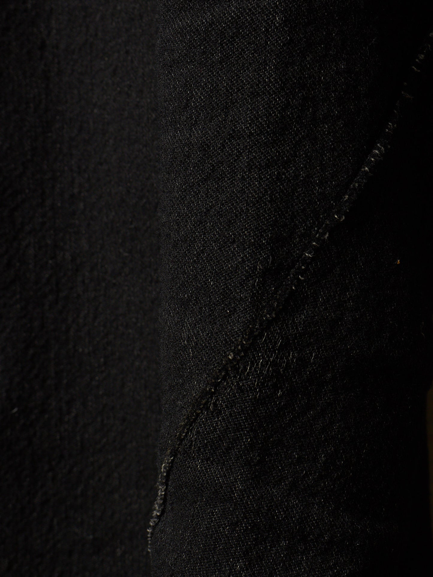 Close-up of black textured fabric with a diagonal seam running through the center.