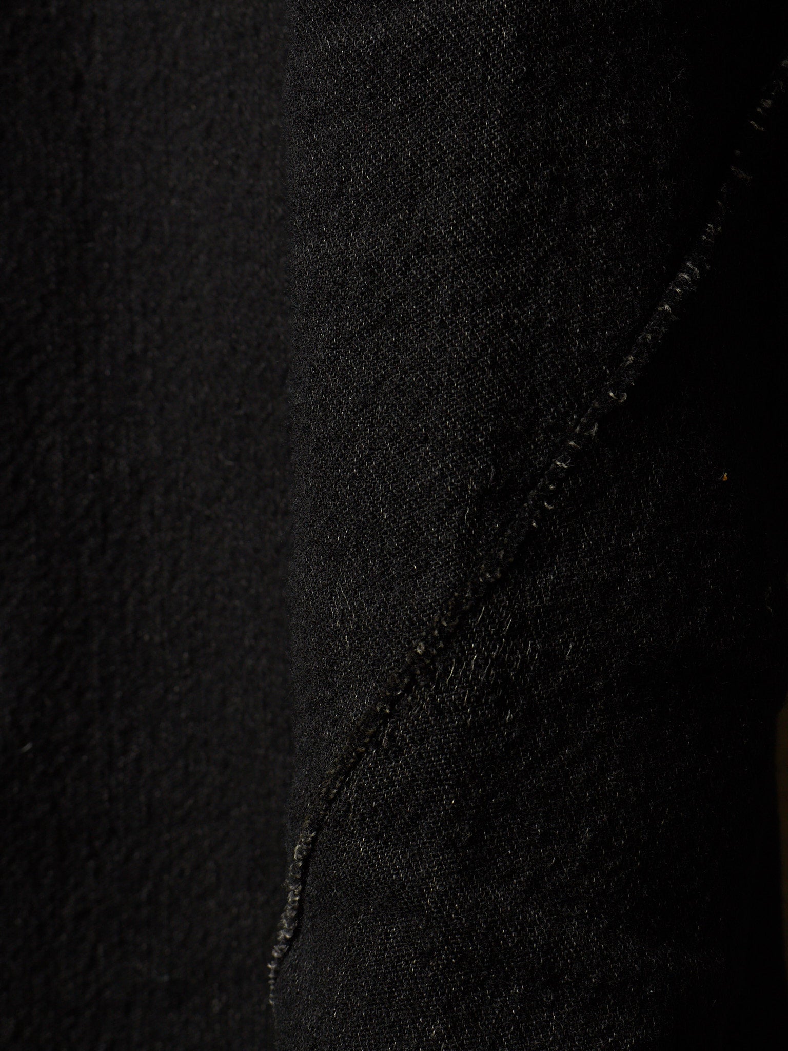 Close-up of black textured fabric with a diagonal seam running through the center.