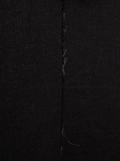 Close-up of black fabric with a central vertical seam and visible loose thread ends.