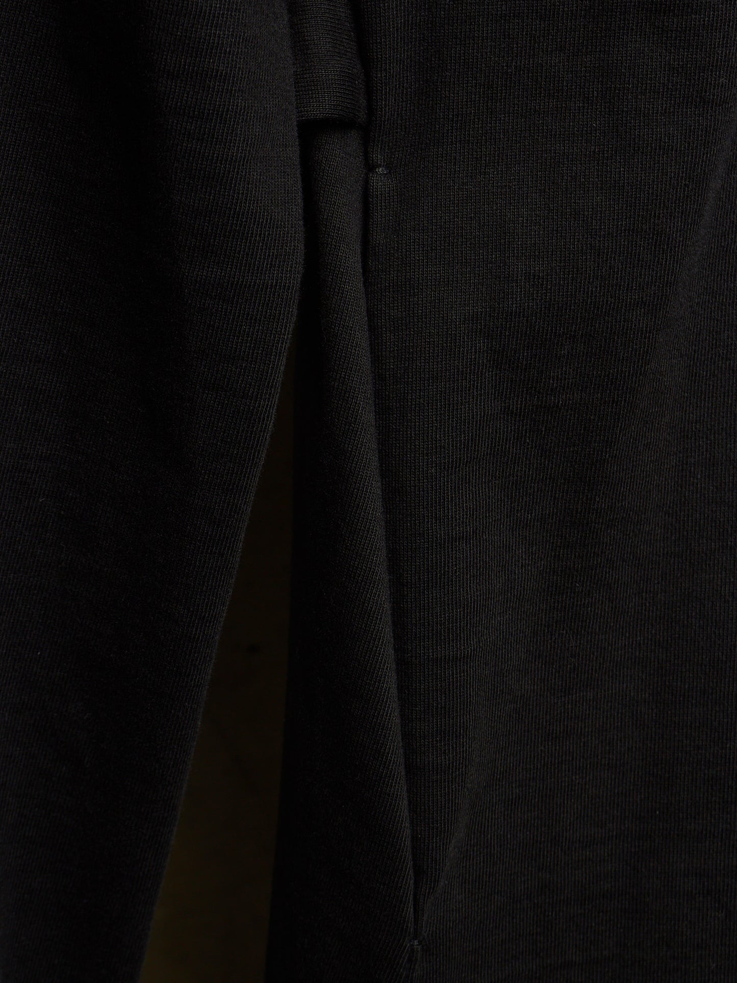 Close-up of a black ribbed knit fabric, showing the texture and a fold detail.