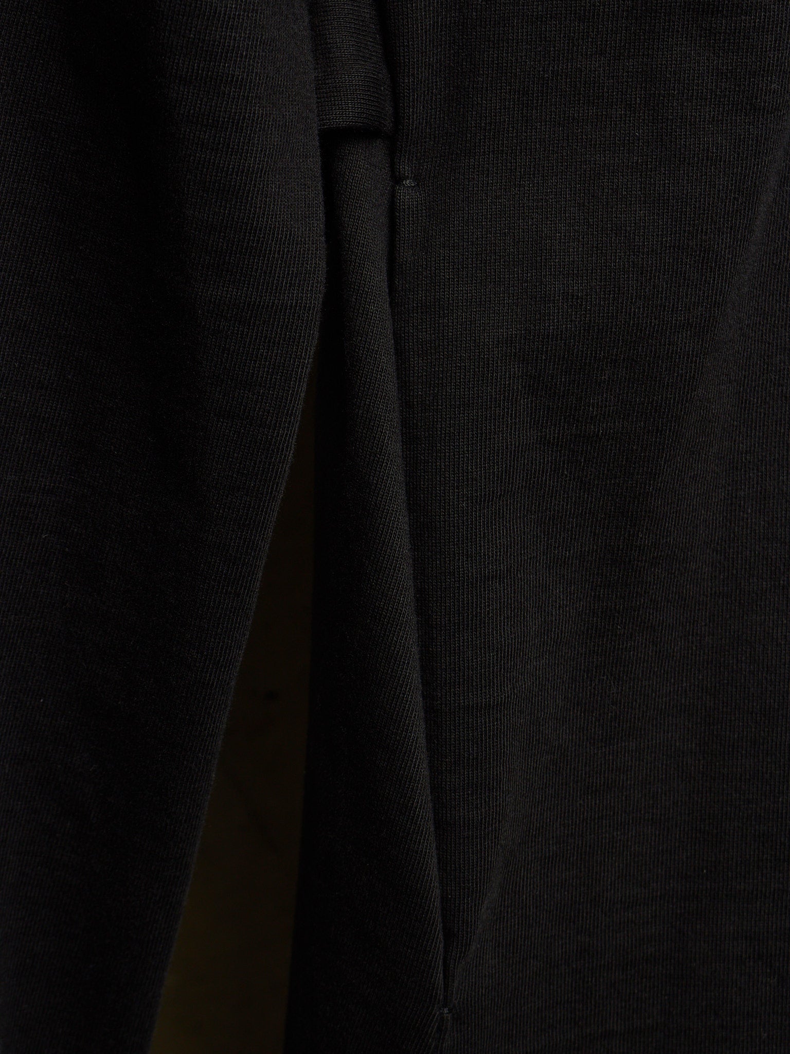 Close-up of a black ribbed knit fabric, showing the texture and a fold detail.