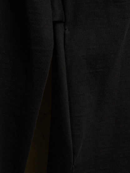 Close-up of a black ribbed knit fabric, showing the texture and a fold detail.