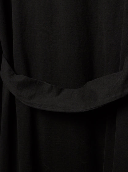 Close-up of a black fabric garment with a wide draped waist belt or sash detail.