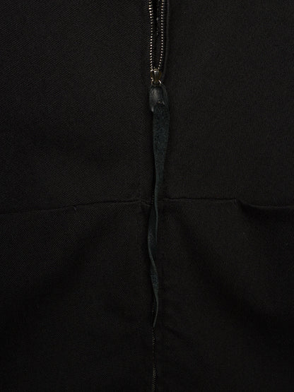 Close-up of a black garment featuring a central zipper with a dark pull tab.