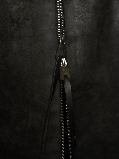 Close-up of a black zipper with a black leather pull tab on a dark textured fabric background.