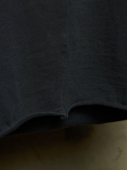 Close-up detail of a dark charcoal gray knit fabric garment, showing the texture and a curved hemline.