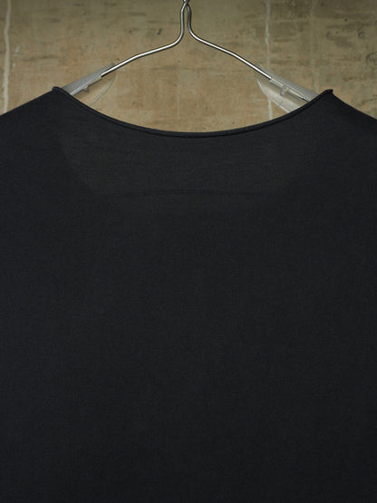 A close-up of a black ribbed knit top hanging on a clear plastic hanger against a beige tiled wall.