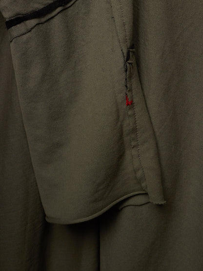 Close-up of olive green fabric with a small red accent stitch detail.
