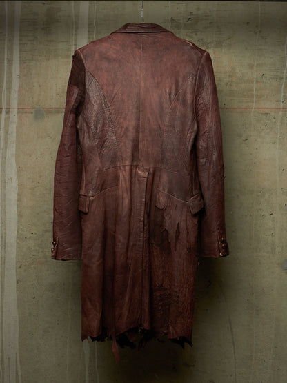 A distressed, dark reddish-brown leather coat hanging against a textured concrete wall, showing the back view with frayed, tattered details.