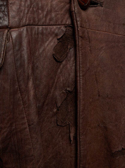 Close-up of a dark brown distressed leather jacket showing the texture, creases, and frayed edges.