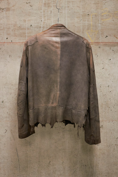 Brown leather jacket on a hanger against a textured beige wall.
