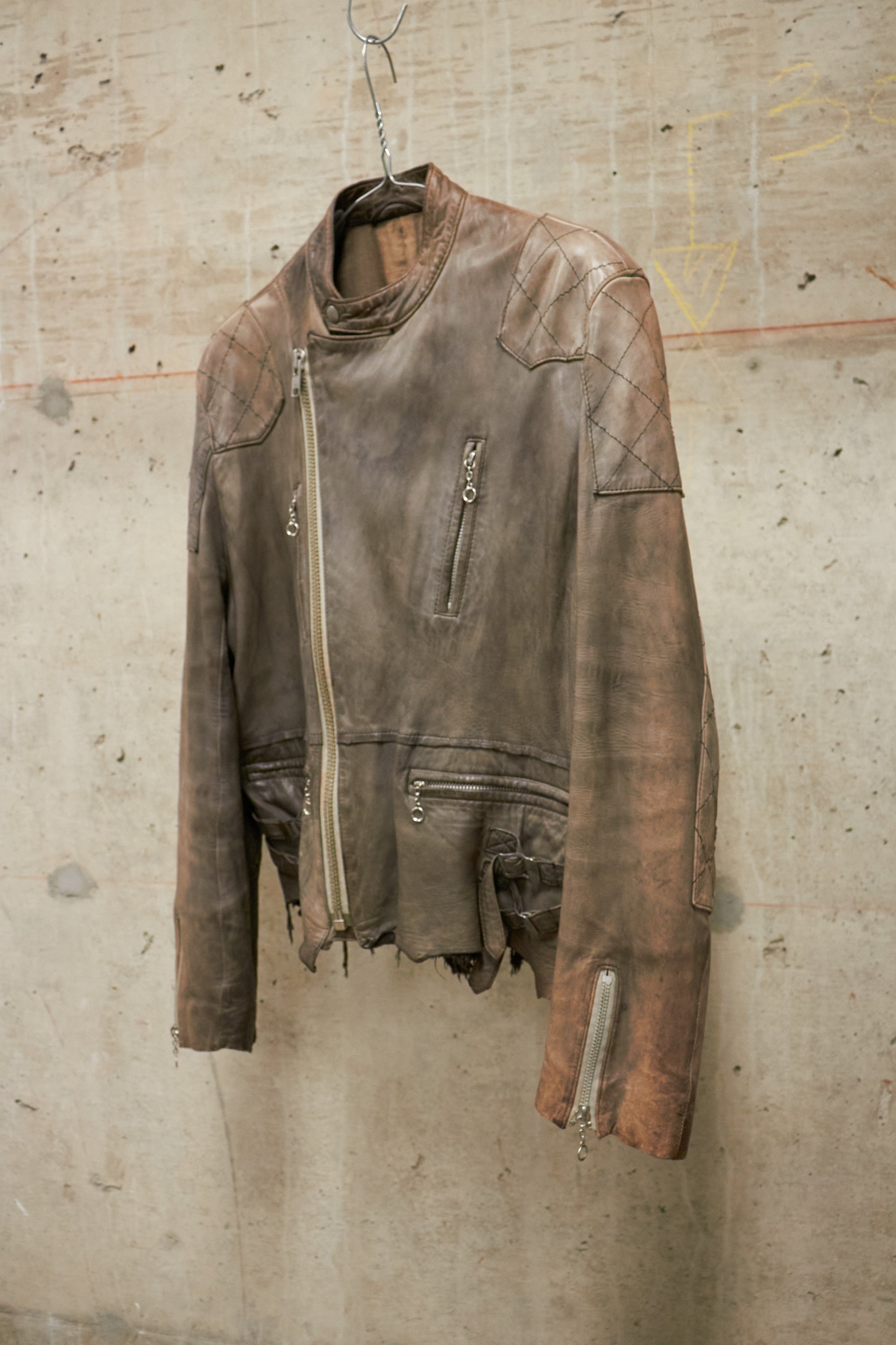 Brown leather jacket hanging on a textured wall