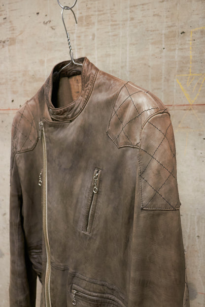 Brown leather jacket hanging on a hook against a textured wall.