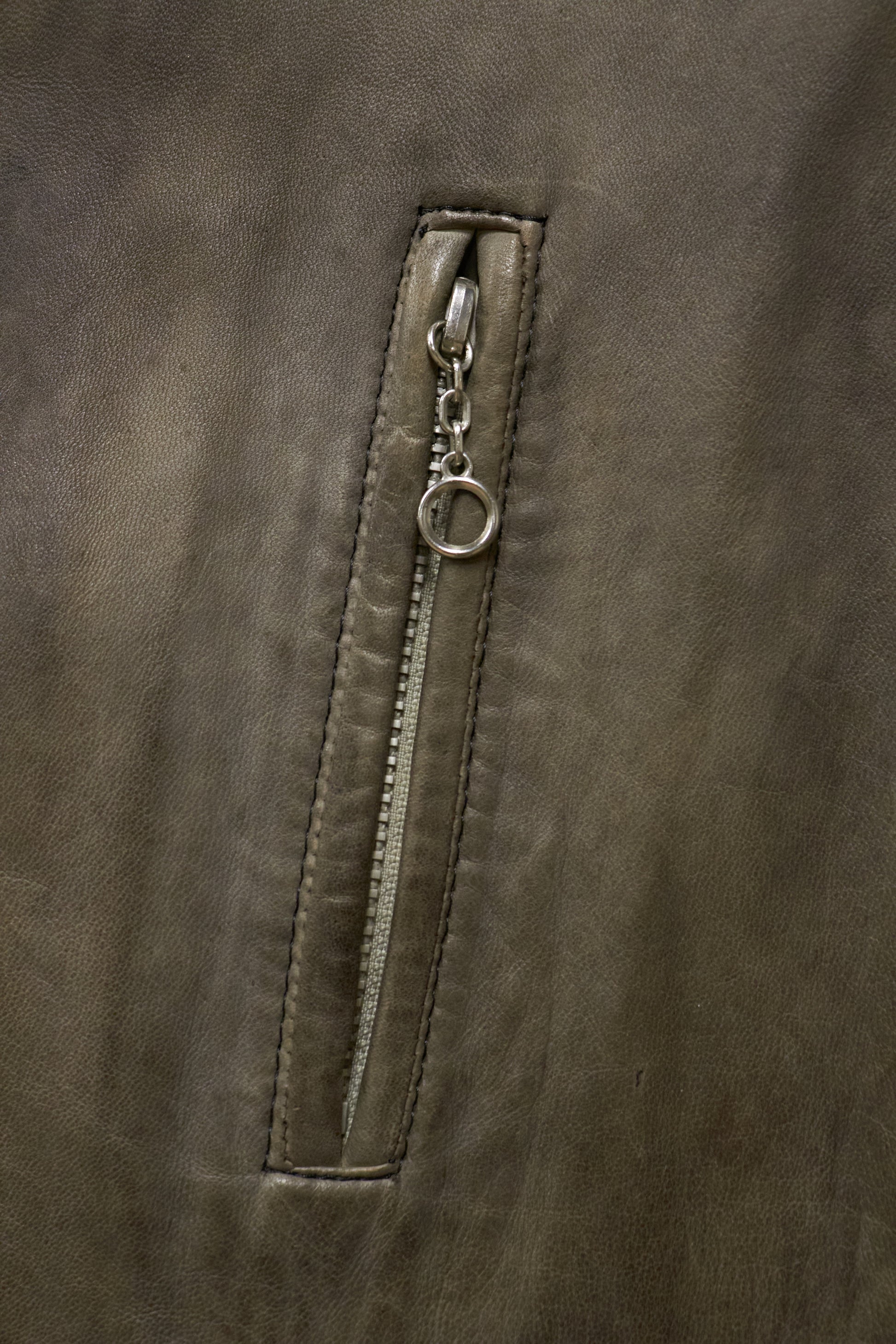 Close-up of a zipper on a brown leather jacket
