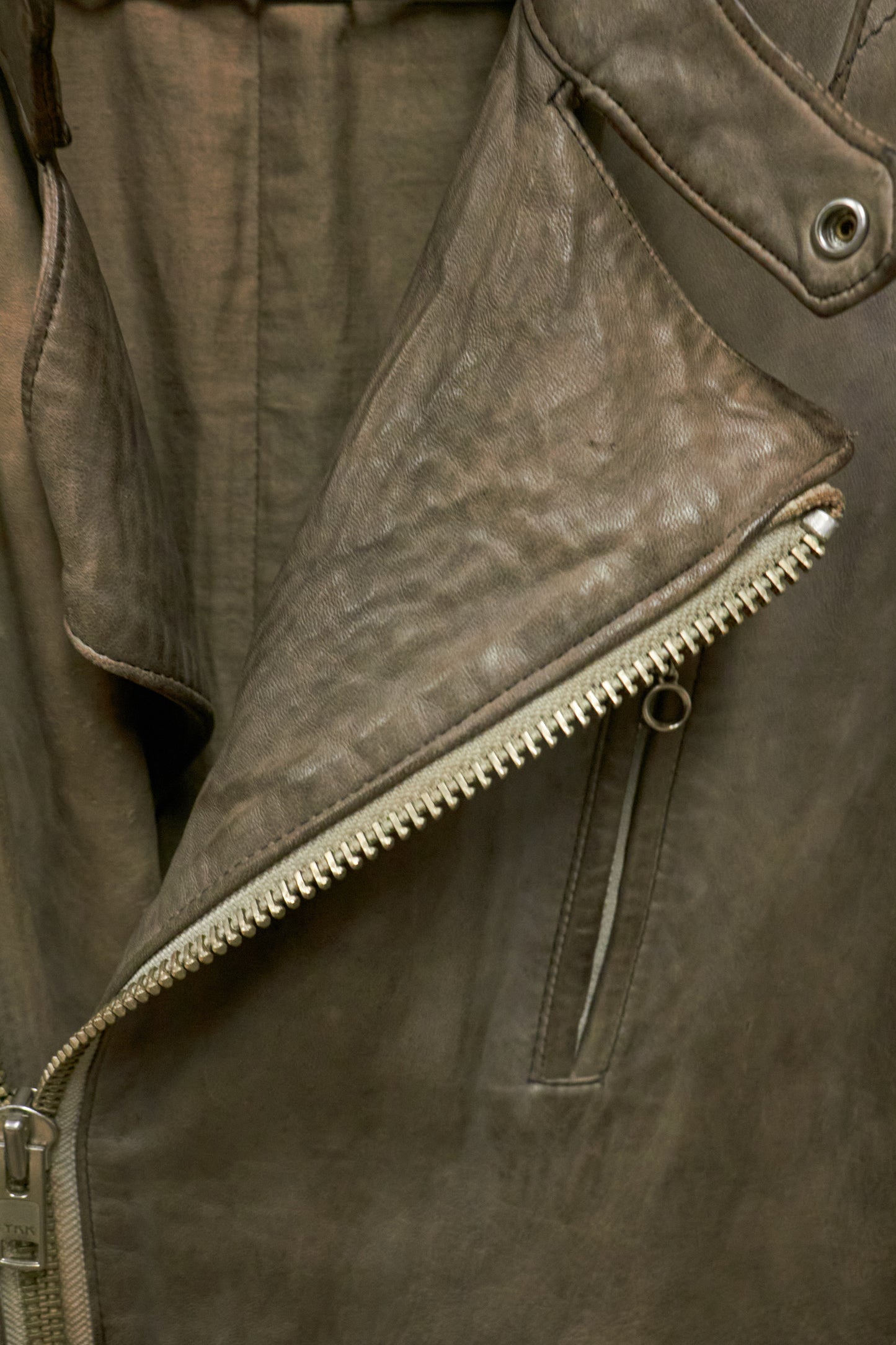Close-up of a brown leather jacket with zipper details