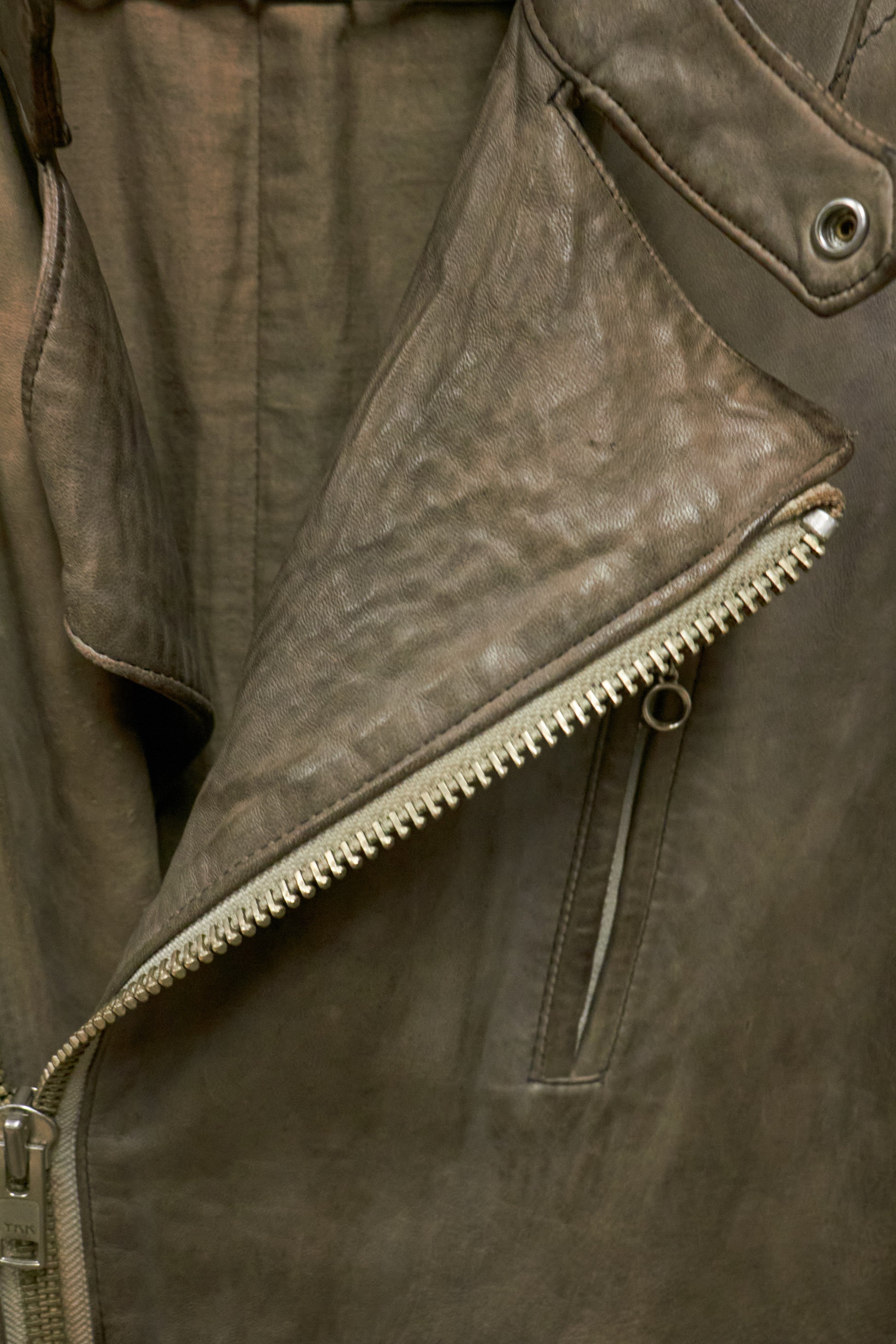 Close-up of a brown leather jacket with zipper details