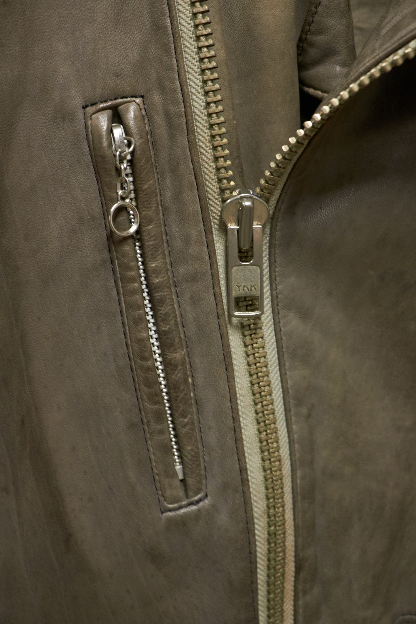 Close-up of a brown leather jacket with a zipper