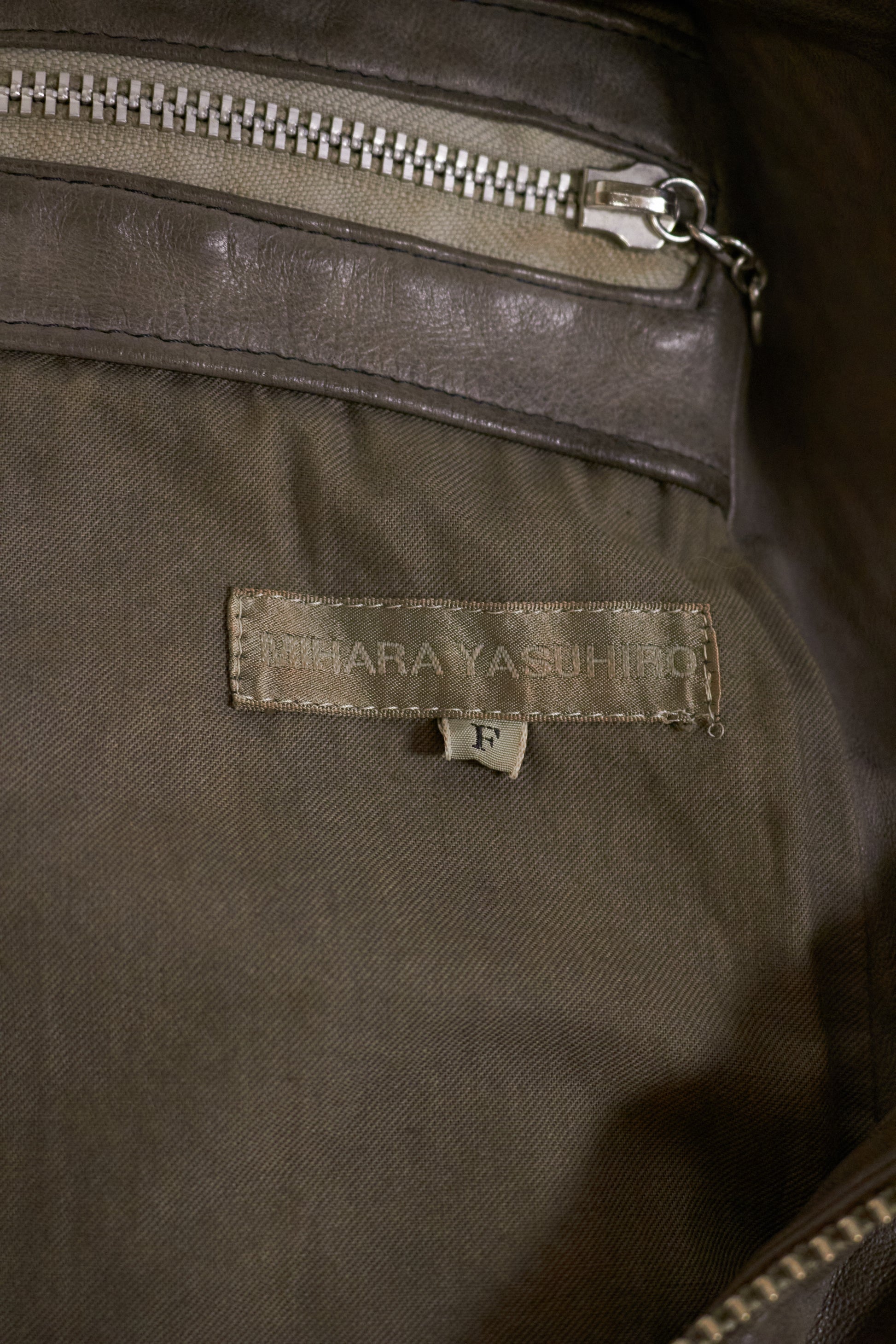 Close-up of a brown fabric with a brand label and zipper.
