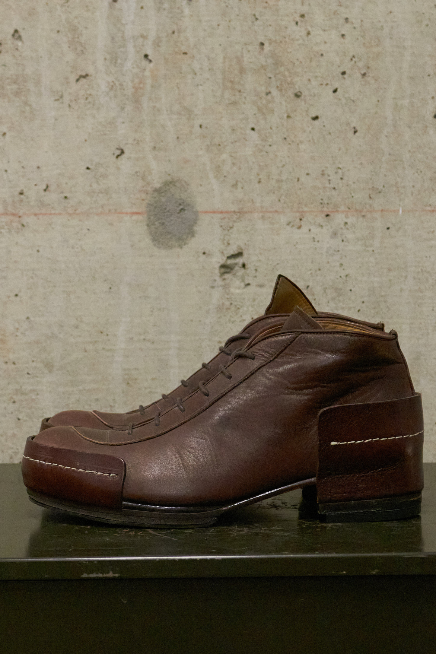 Brown leather shoe on a textured surface with a neutral background