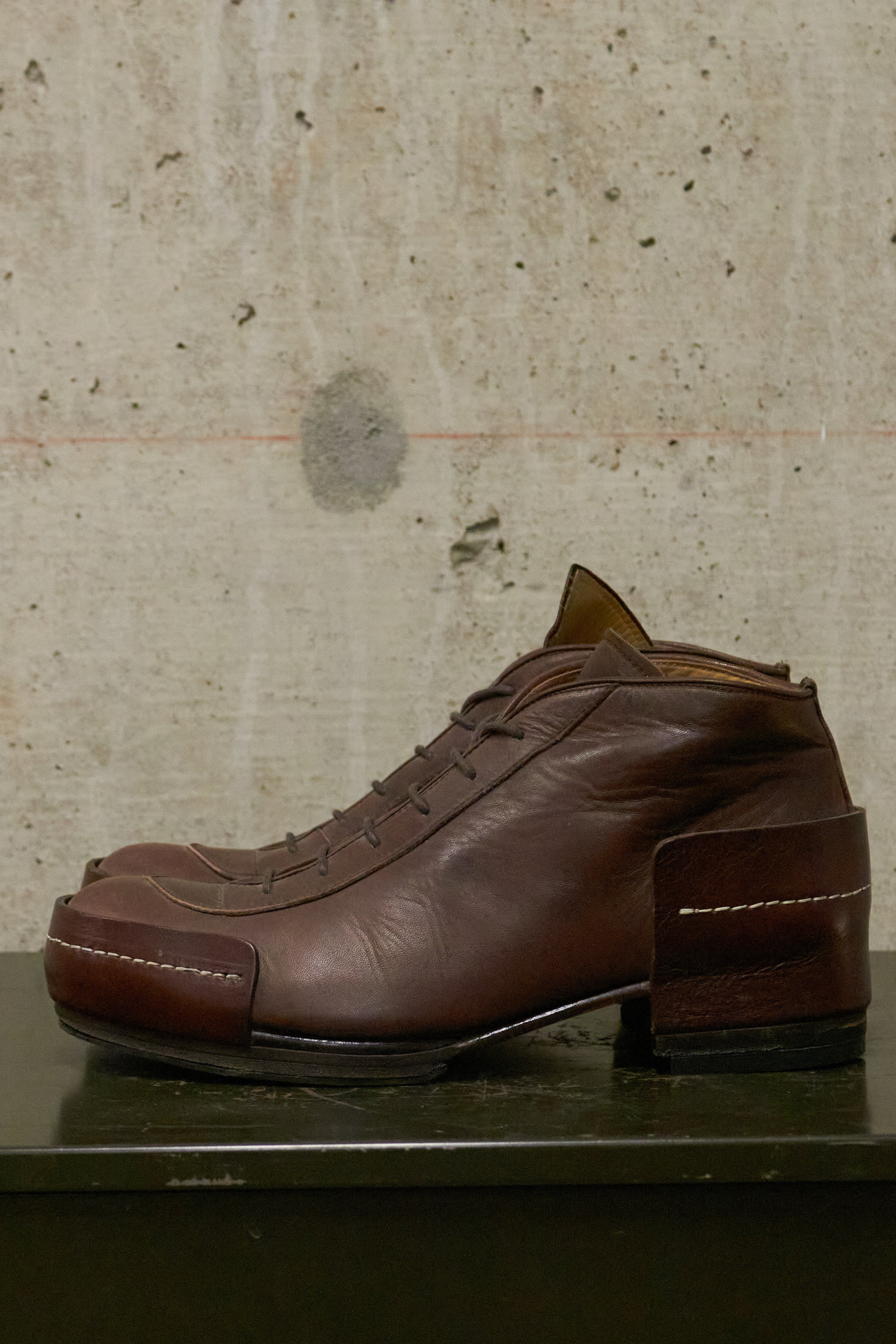Brown leather shoe on a textured surface with a neutral background