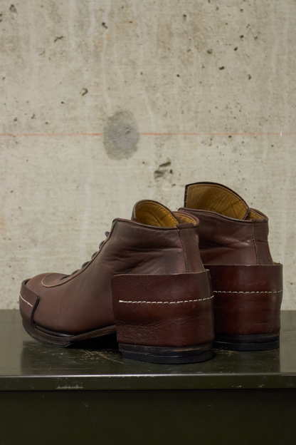 Pair of brown leather shoes on a metallic surface with a textured beige wall background