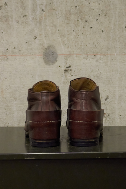 Pair of brown leather shoes on a metallic surface with a textured wall background